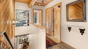 Un interior de madera con zona de comedor, un pasillo con puertas y un espejo grande.