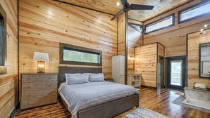 Camera da letto in una baita di legno, con un letto, un comodino e una ventola a soffitto.