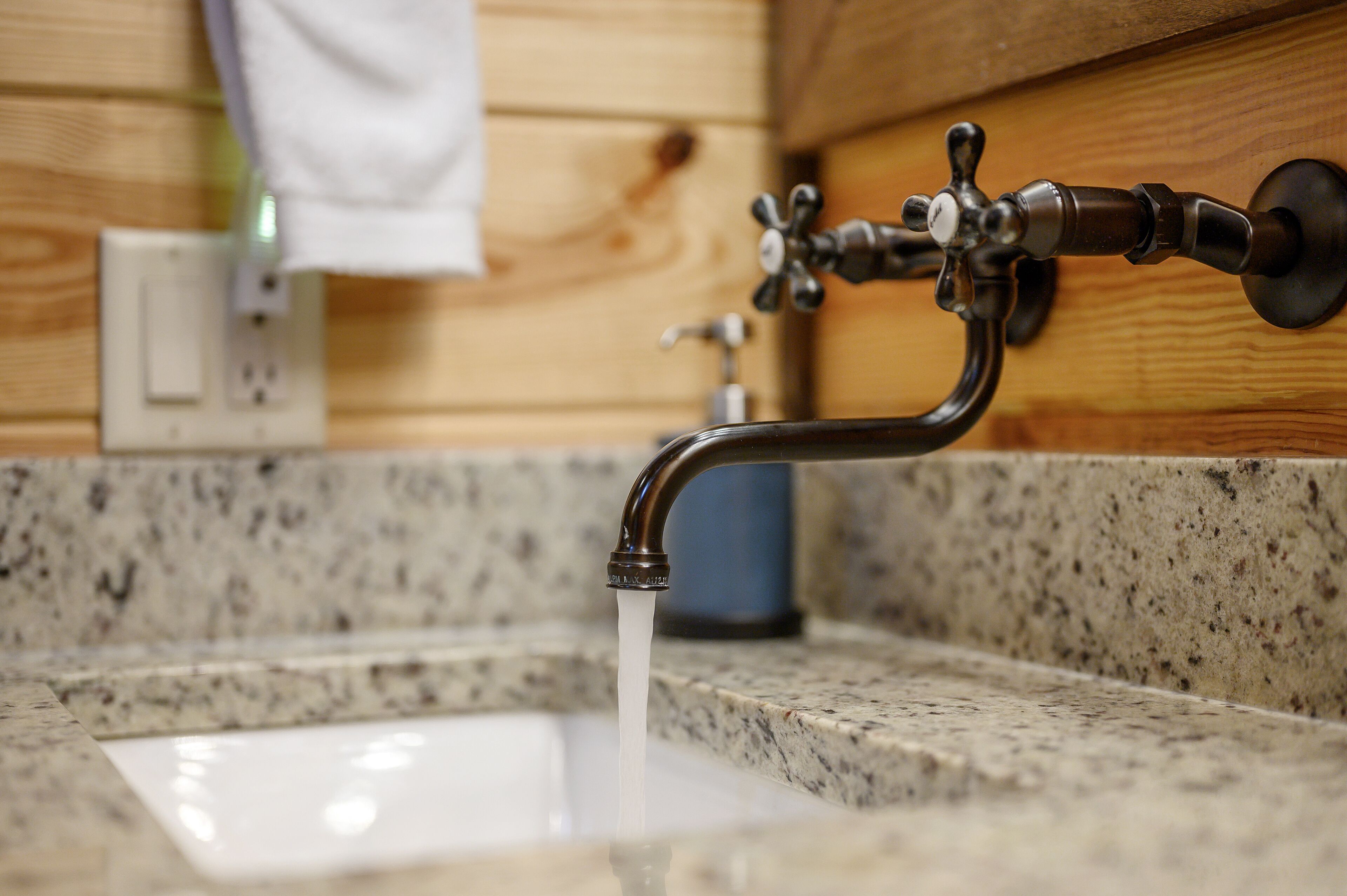 A bathroom sink with a modern faucet and a wooden wall.