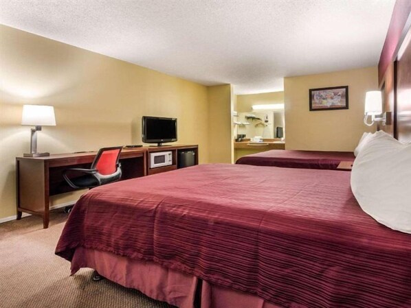 A hotel room with two beds, a desk with a computer and a TV, a microwave, and a lamp. - Ramada Limited Gilroy (Gilroy)
