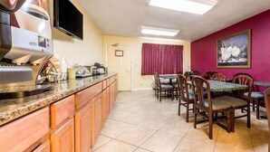 A kitchen with a built-in microwave, a coffee maker, and a toaster. There is a dining area with a table and chairs. - Ramada Limited Gilroy (Gilroy)