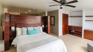 A bedroom with a large bed, wooden headboard, a ceiling fan, and a wardrobe. - Zimmer Suites (Aguascalientes)