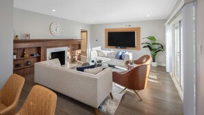 Una sala moderna con sofá, sillones, chimenea, televisor de pantalla plana y un ventanal grande.