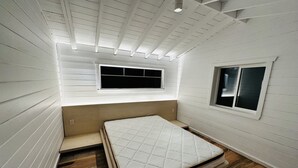 A compact room with a single bed, a small window, and a sloped ceiling with skylights. - Lake Rosseau Sunset Facing Deep Water Lake Front Property (Port Carling)