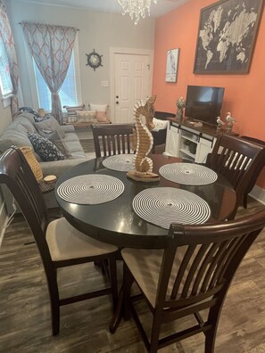 A dining area with a round table, chairs, and black and white patterned placemats.
