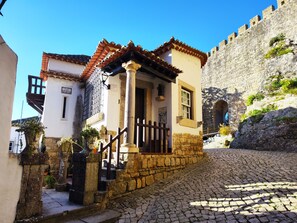 A cobblestone street with a small building featuring a tiled roof and stone walls.