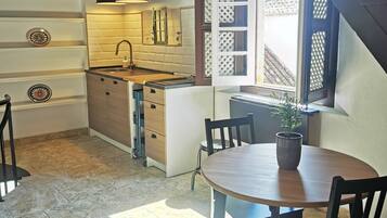 A kitchen with a wooden ceiling, a sink, cabinets, and a dining area with a table and chairs.