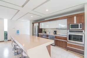 Une cuisine moderne dotée d’un îlot central, d’appareils électroménagers en acier inoxydable et de meubles de rangement en bois.