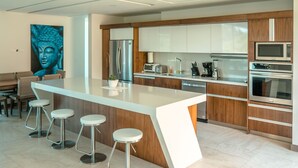 A modern kitchen with a central island, bar stools, stainless steel appliances, and wooden cabinetry. - Luxury Villa Los Pajaros Private Pool & Oceanview (Playa Hermosa)