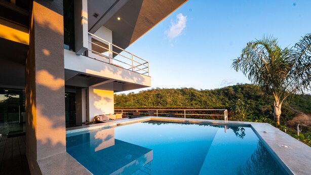 A modern pool area with a clear view of a lush hillside. - Luxury Villa Los Pajaros Private Pool & Oceanview (Playa Hermosa)