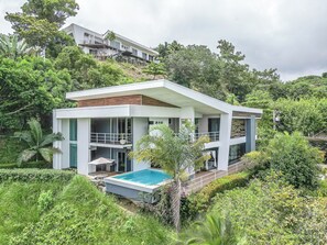 Una casa moderna amb piscina, envoltada de vegetació exuberant.