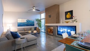 Ein modernes Wohnzimmer mit einer Couch, einem Couchtisch und einem Kamin. Es gibt einen Essbereich mit einem Tisch und Stühlen.
