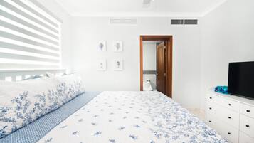 Quarto com cama, penteadeira, televisão e porta para o banheiro.