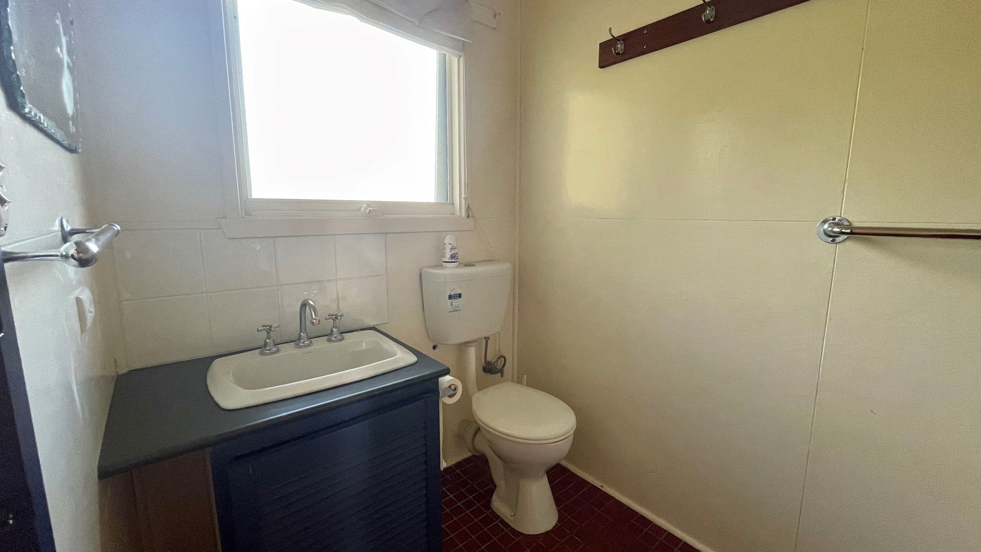 A small bathroom with a sink, toilet, and window.