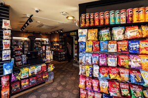 Un pasillo con varios tipos y marcas de papas fritas, palitos de pretzel y otros bocadillos.