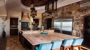 A spacious kitchen with a large island, stone walls, and modern appliances. - Long Term Rental Family Style Villa with Oceanview  (San Jose del Cabo)