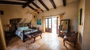 A bedroom with a bed, a bench, a chair, a mirror, and a ceiling fan. - Long Term Rental Family Style Villa with Oceanview  (San Jose del Cabo)