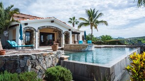 A poolside area with a stone wall, lounge chairs, and a pool. - Long Term Rental Family Style Villa with Oceanview  (San Jose del Cabo)