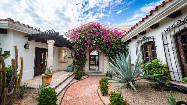 A courtyard with a tiled pathway, a pergola, cacti, and flowering plants. - Long Term Rental Family Style Villa with Oceanview  (San Jose del Cabo)