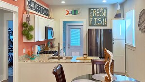 Uma cozinha moderna com uma ilha central, uma área de jantar com mesa e cadeiras redondas, e arte decorativa na parede.