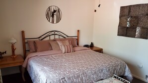 Ein Schlafzimmer mit einem Bett, Nachttischen, einer Wanduhr, einem kleinen Teppich und einer Bank.