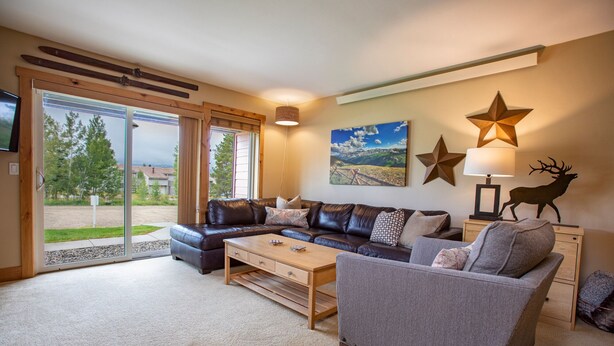 A spacious living room with a large sofa, a smaller armchair, and a coffee table. There is a painting on the wall and a star decoration. - Amazing 2bd/2ba condo!  Custom updates, stellar amenities and prime location! (Fraser)