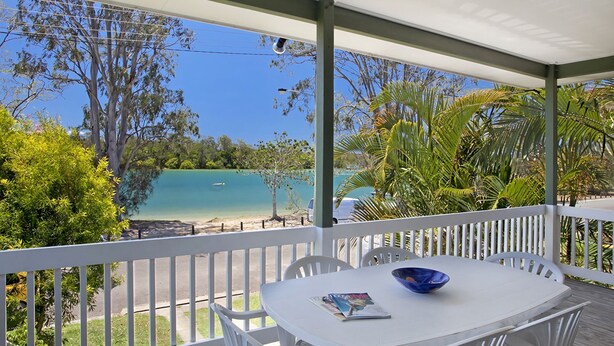 Un espace extérieur aménagé, abrité et doté d’une table et de chaises, offrant une vue sur une plage et des eaux turquoise.
