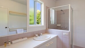 Une salle de bain moderne avec un grand miroir, un lavabo et une douche.