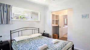 Une chambre à coucher avec un lit, une table de chevet et une fenêtre avec des stores.