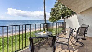 A balcony with a table and chairs, overlooking a beach and the ocean. - Ma'alaea Surf, D9 - Oceanfront Condo - remodeled two-bedroom, 2nd Floor (Kihei)