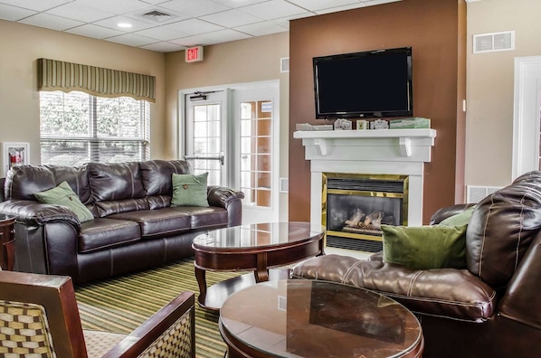 A furnished living room with leather sofas, a fireplace, a flat-screen TV, and a large window. - The Suites at Hershey (Hershey)