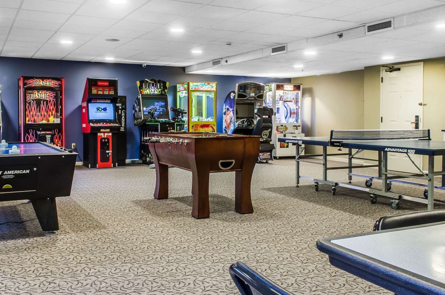Una sala de recreación con una mesa de fútbol de mesa, una mesa de billar y varios juegos de arcade.