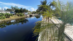 Een rustig water met een brug, palmbomen en gebouwen op de achtergrond.