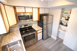 Een moderne keuken met roestvrijstalen apparatuur, houten kasten en een marmeren aanrecht.