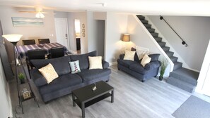 Een moderne woonkamer met een bank, salontafel en een eethoek met een tafel en stoelen.