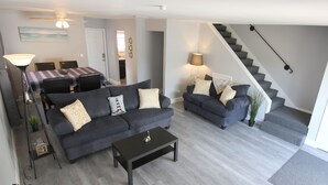 Een moderne woonkamer met twee banken, een salontafel en een eethoek met een geruit tafelkleed.