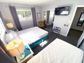 Een hotelkamer met een bed, een stoel, een televisie, een raam en een spiegel.