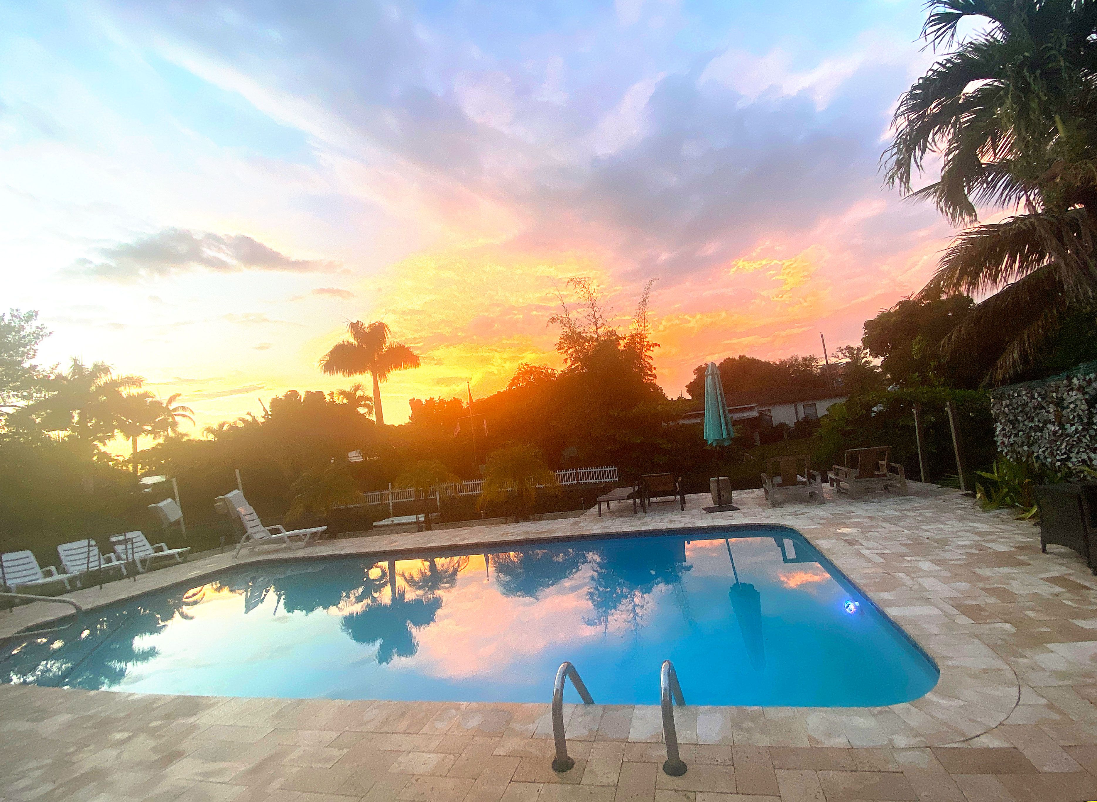 A swimming pool with lounge chairs and a fence in the background.