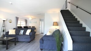 Een moderne woonkamer met een zithoek, een eethoek en een trap.