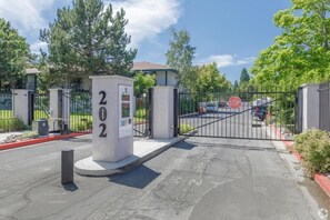 Enter a residential area with a secure gated entrance and lush surroundings.