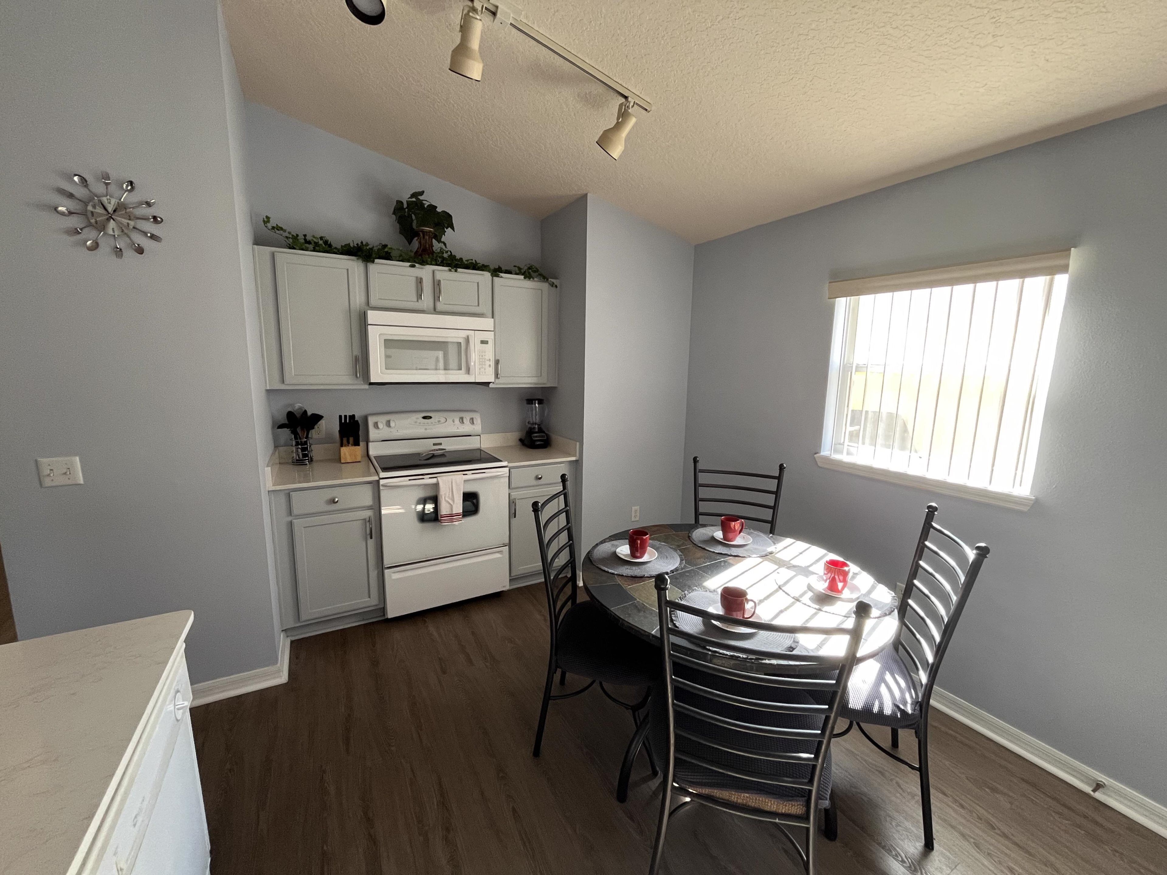 A kitchen with white cabinets, a microwave, an oven, and a dining table with chairs.