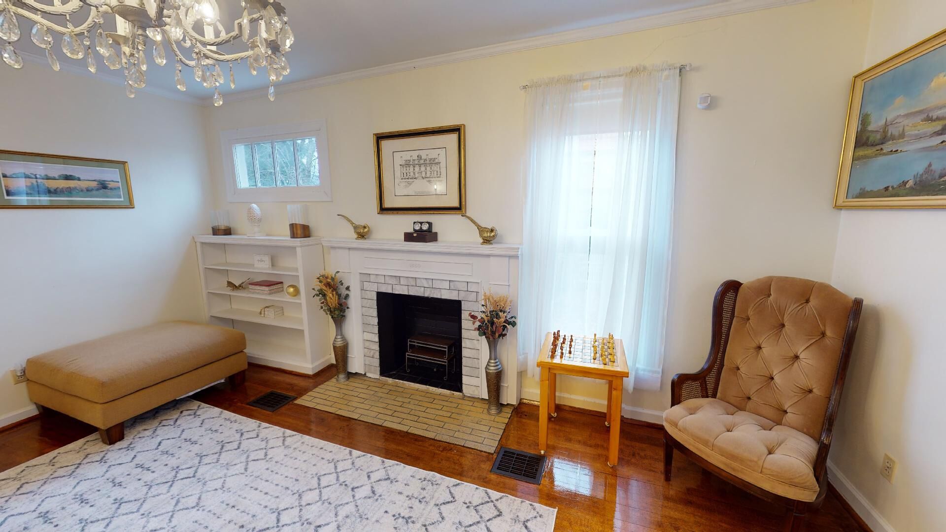 Una sala de estar con chimenea, un sofá, una silla y una mesa de ajedrez.