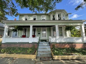 A two-story house with a porch, brick foundation, and a number '100' on the front.