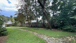 Ein Garten mit einem Kiesweg, grünem Rasen und Bäumen.