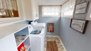 A laundry room with a washing machine, dryer, and a small rug on the floor.