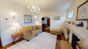 A living room with a sofa, a coffee table, a fireplace, and a chandelier.