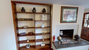 A wooden bookshelf with various decorative items, a framed picture above a fireplace, and a globe on a table.