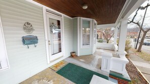 A covered porch with a wooden ceiling, a mailbox, and a welcome mat.