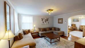 A living room with a sofa set, a coffee table, a lamp, a world map artwork, and a chandelier.