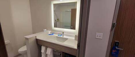 A modern bathroom with a white sink, mirror, and toilet.